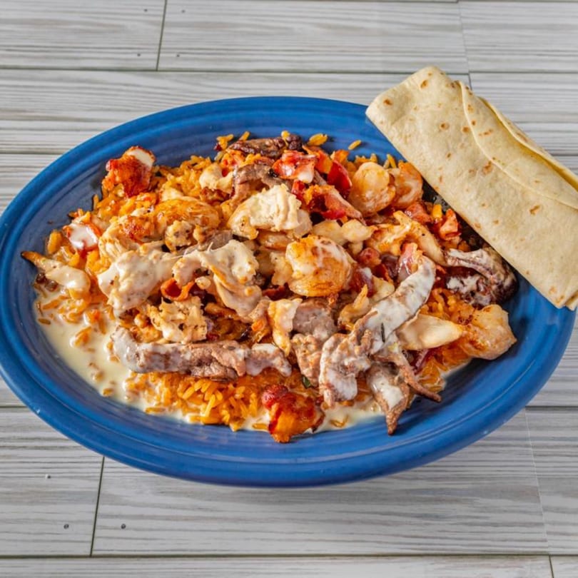 El Sazon Mexican Grill's Arroz con Mariscos, a vibrant mix of seafood, rice, and creamy sauce with a tortilla.