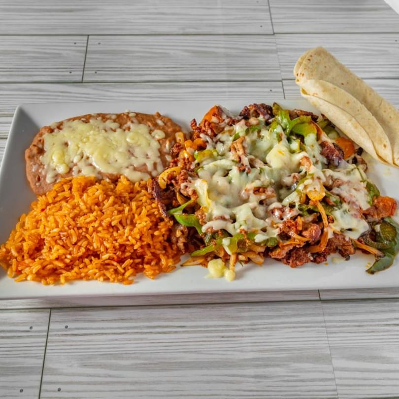 El Sazon Mexican Grill's fajita plate with rice, refried beans, and tortillas on a white platter.